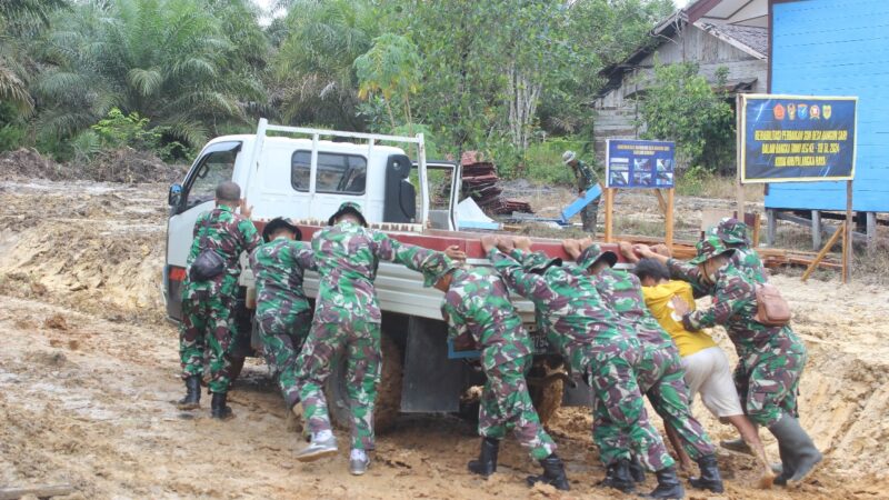 Kondisi Jalan Licin, Personil Satgas TMMD ke 119 Bantu Dorong Mobil Warga